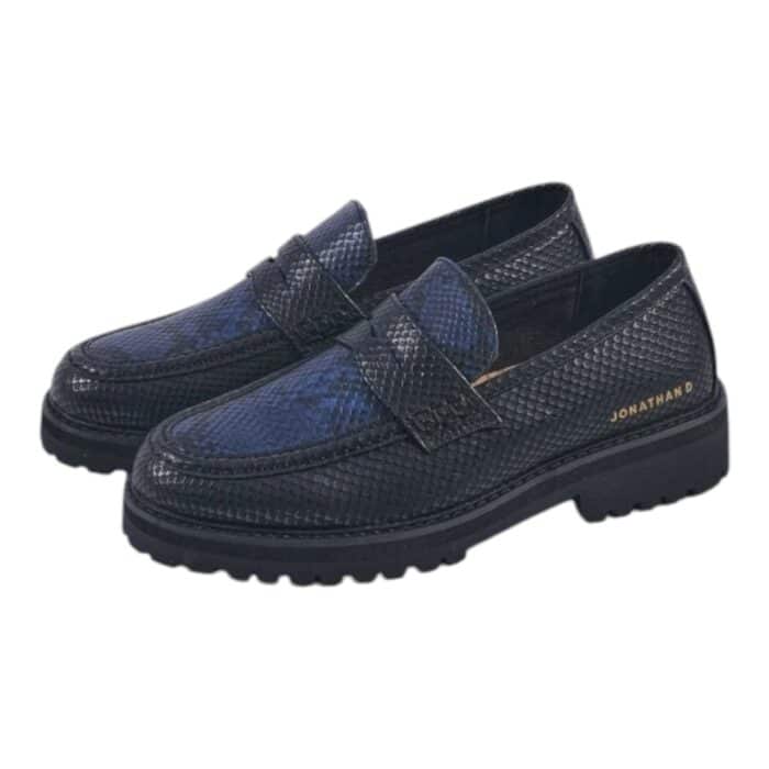 55 121 C | The Jonathan D Penny Moc Snake Eclipse in Black/Blue is a sophisticated yet contemporary loafer, designed with a high-quality PU upper that mimics the sleek appearance of genuine leather while ensuring durability and long-lasting wear. Featuring a striking black and blue color combination, this shoe seamlessly blends classic penny loafer elements—such as moccasin-style stitching and a contrast band across the vamp—with modern details like the iconic golden JONATHAN D branding at the back, making it an effortlessly stylish choice for both formal and casual occasions. With a cushioned footbed for superior comfort, a breathable interior lining to keep your feet cool, and a thick rubberized sole for excellent grip and support, this loafer not only elevates your style but also provides all-day comfort and stability for any setting.